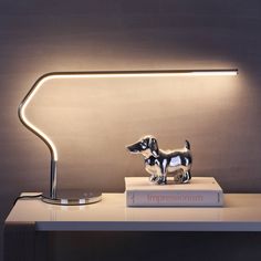 a dog figurine sitting on top of a book next to a lamp