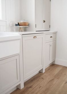 a kitchen with white cabinets and wood floors