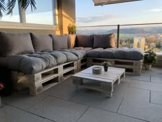 a couch and coffee table sitting on top of a patio next to a large window