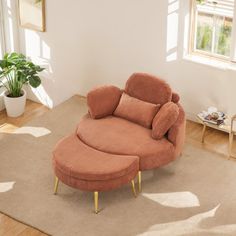 a living room with a chair and ottoman in the corner, next to a potted plant