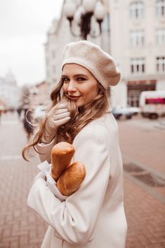 a woman in white coat and hat holding bread