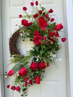 a wreath with red roses and greenery on the front door