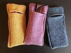 three small crocheted pouches sitting on top of a black table next to each other