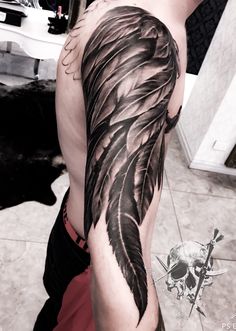 a man with a black and grey feather tattoo on his arm