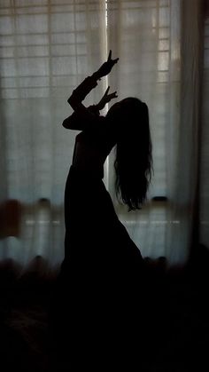 the silhouette of a woman standing in front of a window