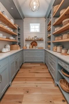 a kitchen filled with lots of wooden shelves next to white counter tops and gray cabinets