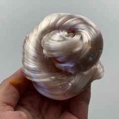 a hand holding a small white object in it's right hand and the top part of its shell visible