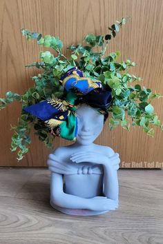 a blue vase with green plants in it on a table next to a wooden wall