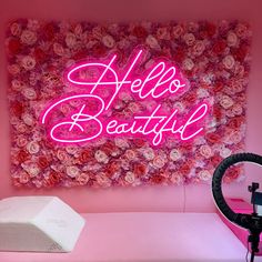 a pink room with a hello beautiful neon sign on the wall and flowers in the corner