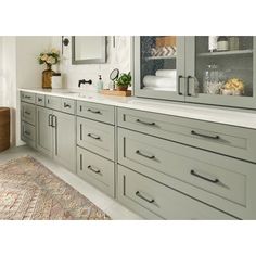 a large bathroom with gray cabinets and white counter tops, along with a rug on the floor