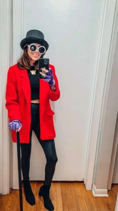 a woman in a red coat and hat taking a selfie