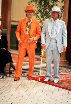 two men in orange suits and white hats standing next to each other on a rug