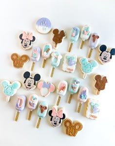 a bunch of mickey mouse and minnie mouse cake toppers on a white table with some cookies in the shape of ears