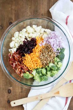 a bowl filled with broccoli, cauliflower, raisins and other ingredients