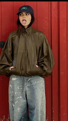 a woman standing in front of a red wall with her tongue out