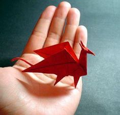 a hand holding a red origami bird