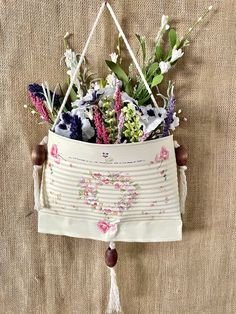 a hanging basket filled with flowers on top of a bed next to a wall mounted planter