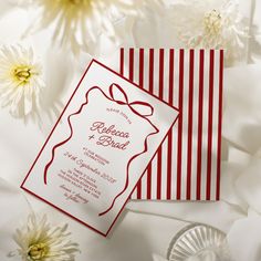 a red and white striped wedding card with a bow on the front is surrounded by flowers