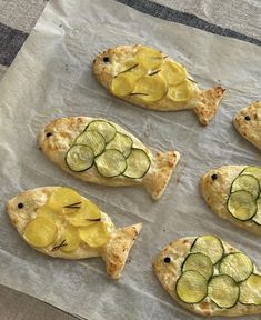 four fish shaped pizzas with cucumber slices on them