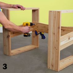 a man working on some wooden furniture with drillers and screwdrivers in his hand