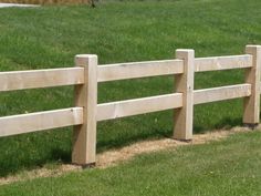 a wooden fence in the middle of a grassy field