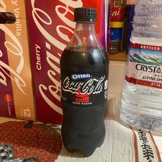 a bottle of coca - cola sitting on top of a table next to other soda bottles