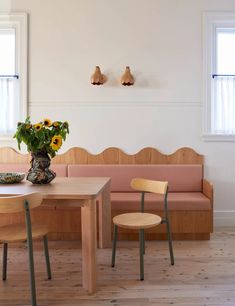 a wooden table with two chairs and a vase filled with flowers sitting on top of it