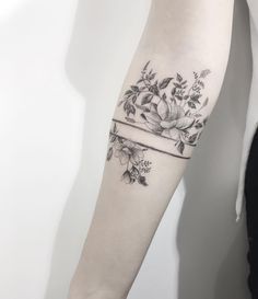 a woman's arm with flowers on it and a ribbon around the wrist tattoo