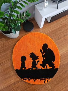 an orange rug with black silhouettes of children on it and a potted plant in the background