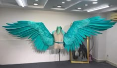 a mannequin with blue wings on display in front of a mirror