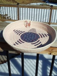 a bowl sitting on top of a wooden table next to a metal fence and snow covered ground