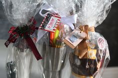 two clear vases filled with pens, markers and pencils wrapped in cellophane