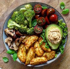 a plate with potatoes, broccoli, tomatoes and avocado