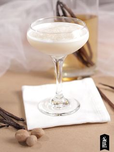 a glass filled with white liquid sitting on top of a table next to a napkin