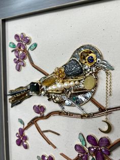 a bird is sitting on a branch with beads and other things hanging from it's back