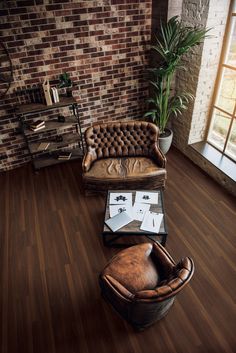 a living room filled with furniture next to a brick wall and floored walls in front of a window