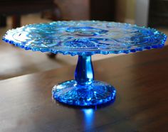 a blue glass cake plate sitting on top of a wooden table next to a couch