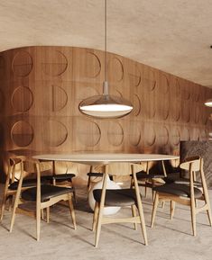 a wooden table with chairs around it and a circular light fixture hanging from the ceiling