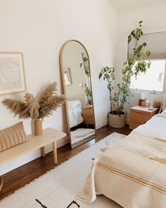 a bedroom with a bed, mirror and plants