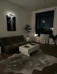 a living room with a couch, coffee table and large window at night in the background