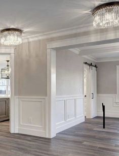 an empty living room with hard wood flooring and chandelier hanging from the ceiling