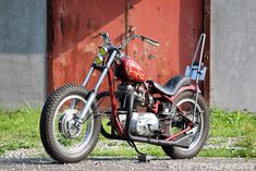 a red and black motorcycle is parked in front of a building with a red door