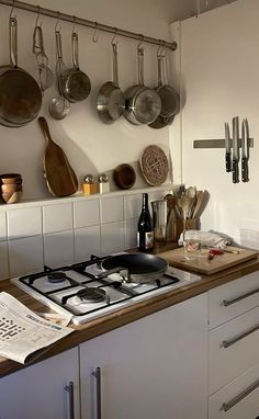 a kitchen with pots and pans hanging on the wall next to a stove top