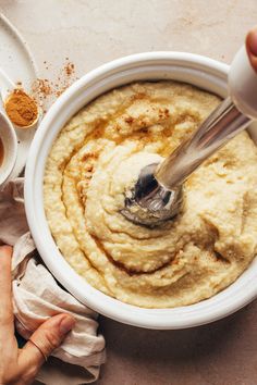 a bowl of hummus with a spoon in it and some spices on the side