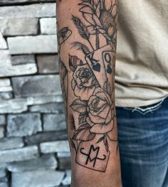 a person with a tattoo on their arm holding a cross and flowers in front of them