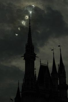 the moon is seen in front of a church steeple with spires against a cloudy sky