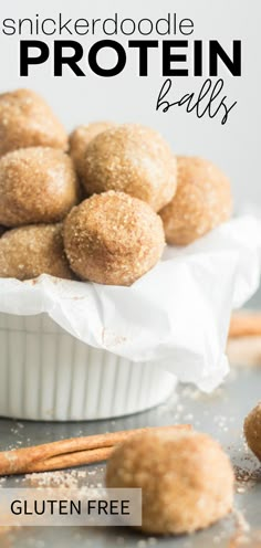 a white bowl filled with gluten free sugar covered protein balls next to cinnamon sticks