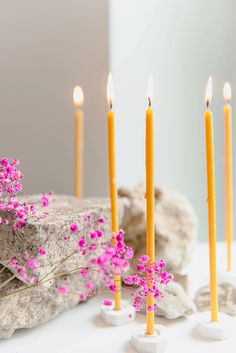 several candles with pink flowers and rocks in the background