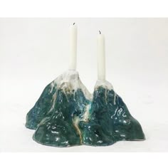 two candles sitting on top of green rocks