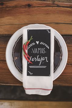 a white plate topped with a piece of food next to a napkin on top of a wooden table